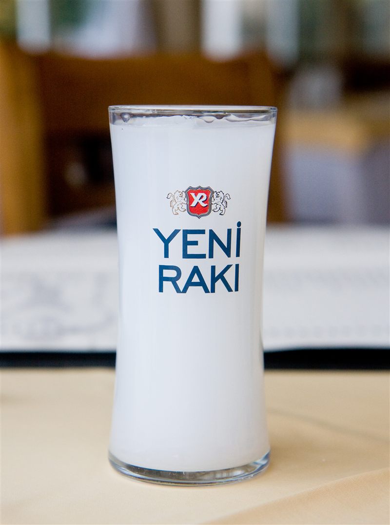 Milky-white rakı, clouded by water, in a tall slender glass